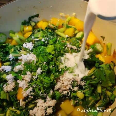 Adding coconut milk, blended coconut, and seasonings for callaloo