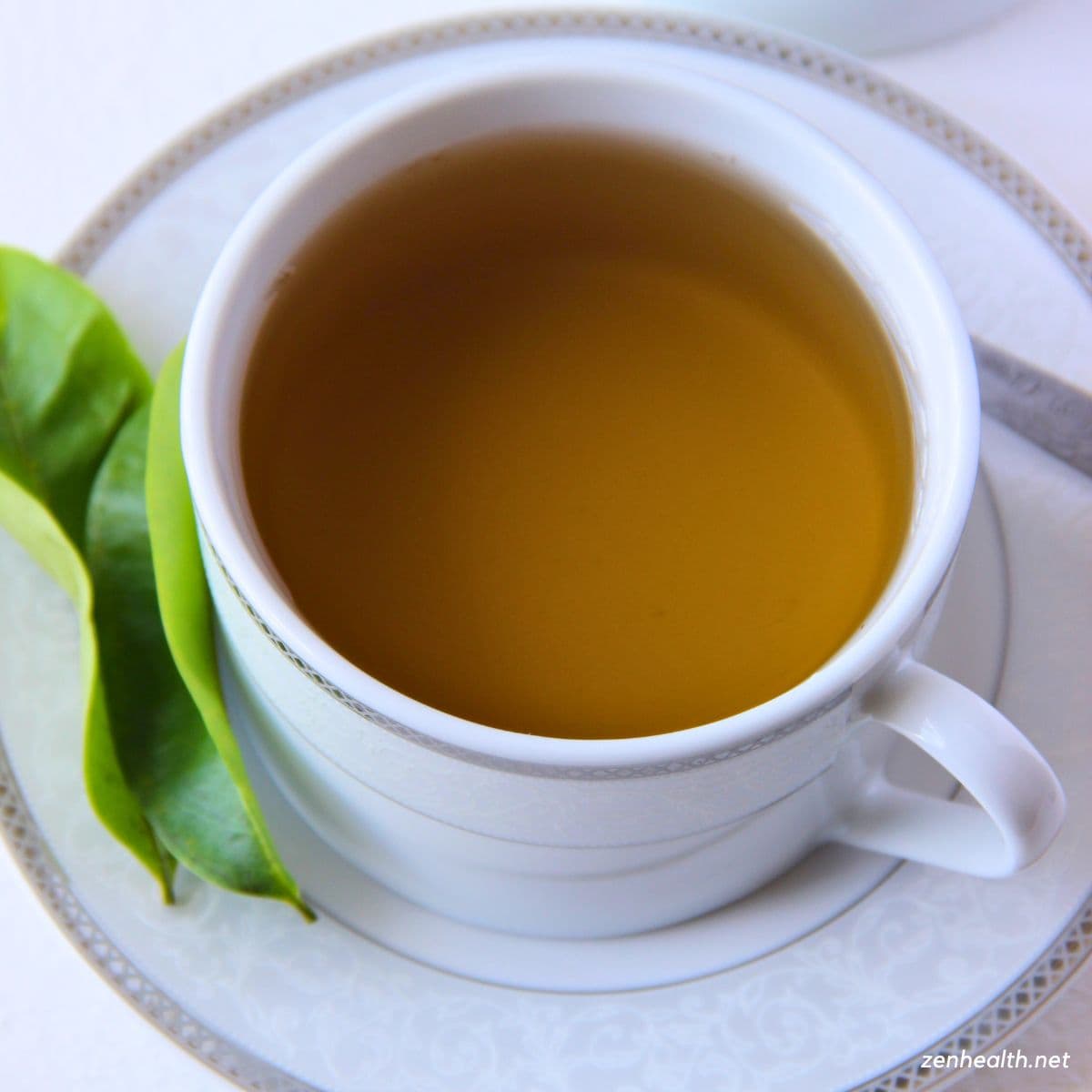 soursop tea in a teacup with soursop leaves on the side