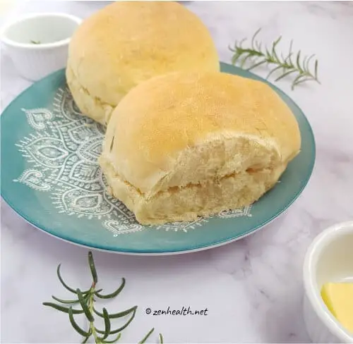 Two baked bread rolls with rosemary and butter
